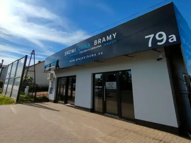 Nowoczesny salon okien i drzwi z dużym banerem reklamowym i numerem 79a.